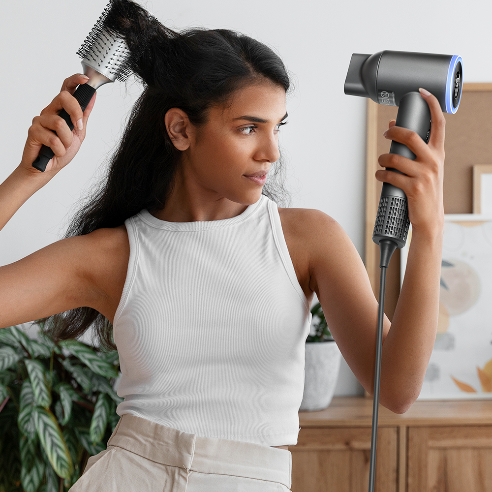 A black woman is styling her hair with her left hand while using the Goolioo high-speed hair dryer with her right hand.